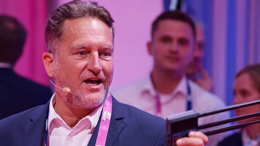 Marco Plannet in der Expo-Area der MyWay 2026 in Berlin, im Gespräch mit dem Publikum, einen Router in der erhobenen Hand