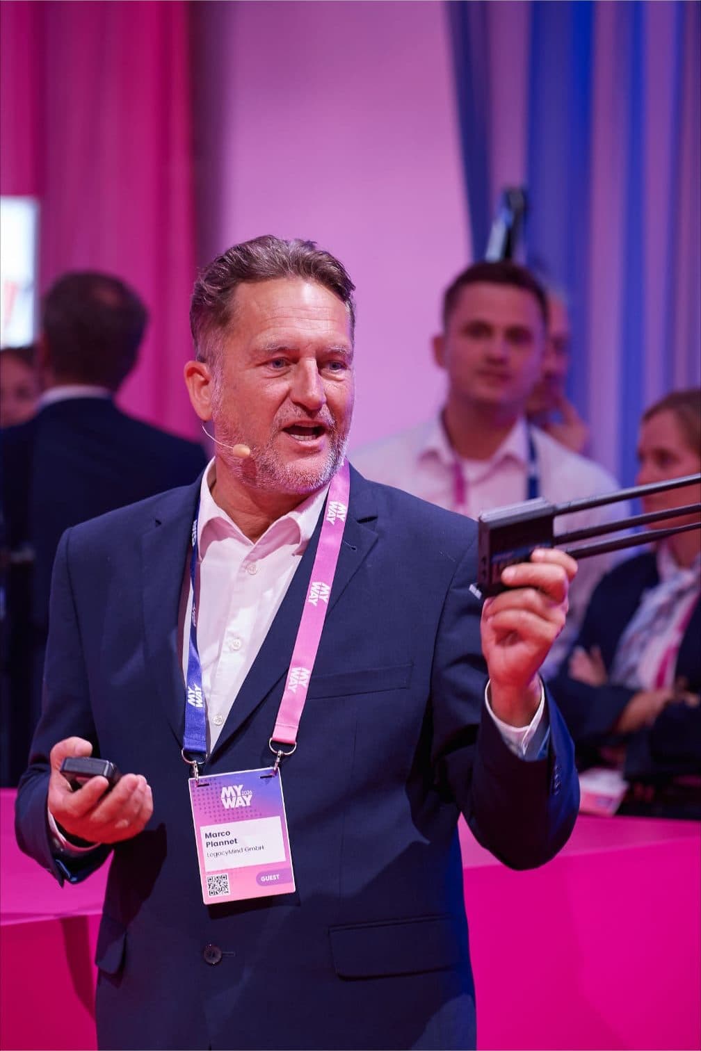 Marco Plannet in der Expo-Area der MyWay 2026 in Berlin, im Gespräch mit dem Publikum, einen Router in der erhobenen Hand